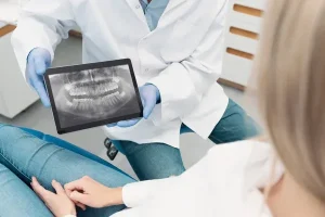 Dentista mostrandole a su paciente una radiografía tomada con herramientas que tienen implementada odontología digital actualizada