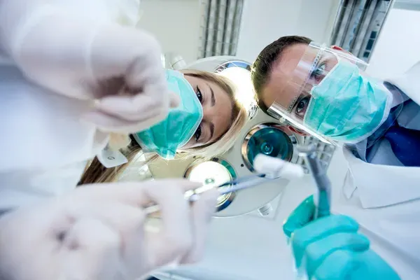 Dos odontólogos en consulta cumpliendo de las normas de bioseguridad en odontología